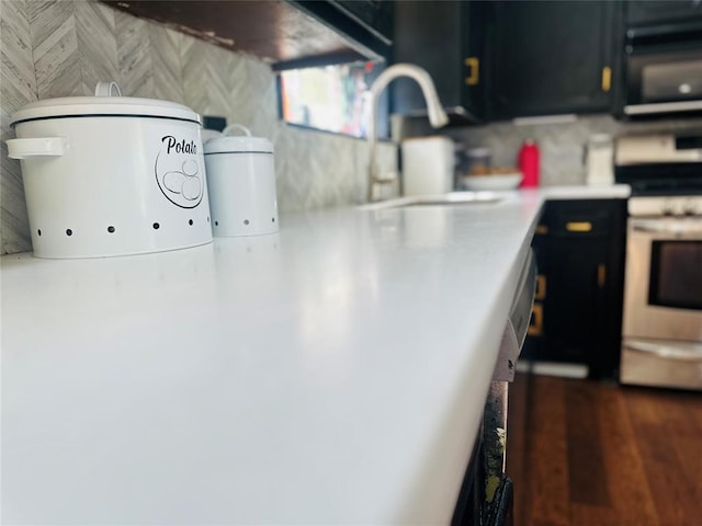 interior space featuring stainless steel electric stove, a sink, dark cabinetry, black microwave, and light countertops