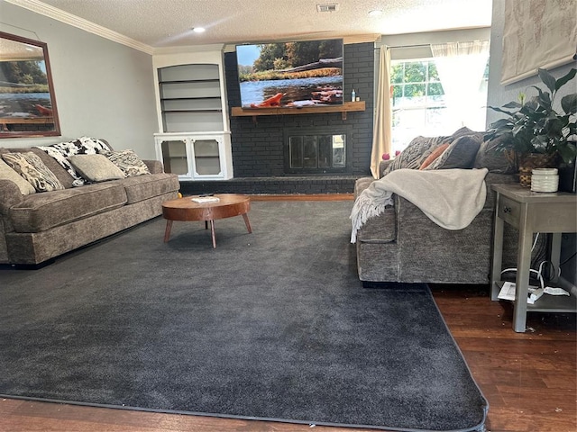 living room featuring wood finished floors, visible vents, ornamental molding, a fireplace, and a textured ceiling