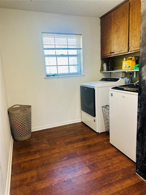 laundry room featuring washing machine and dryer, dark wood finished floors, baseboards, and cabinet space