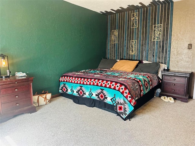 carpeted bedroom featuring a textured wall and baseboards
