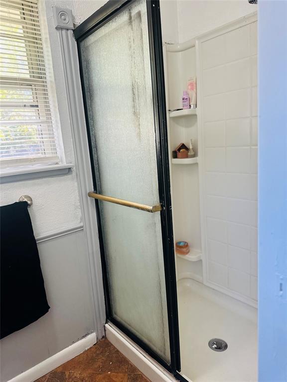 bathroom with baseboards and a stall shower