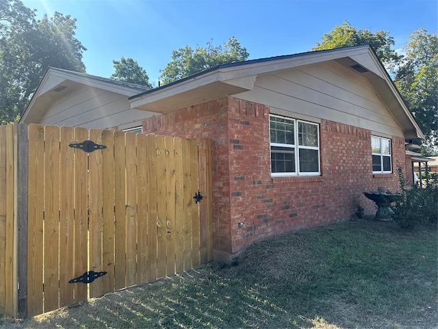 view of property exterior featuring fence and brick siding
