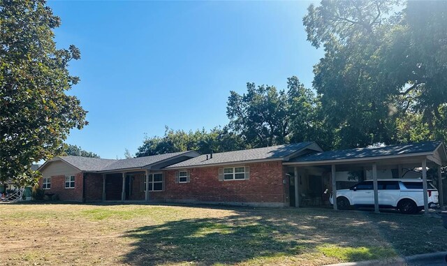 view of front of property featuring brick siding, a front yard, and a carport