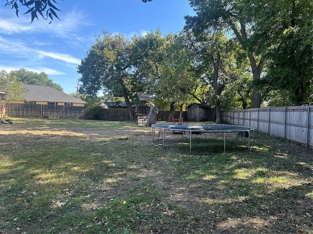 view of yard with a storage shed, a trampoline, a fenced backyard, and an outdoor structure