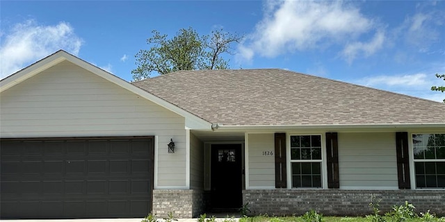 single story home featuring an attached garage, a shingled roof, and brick siding