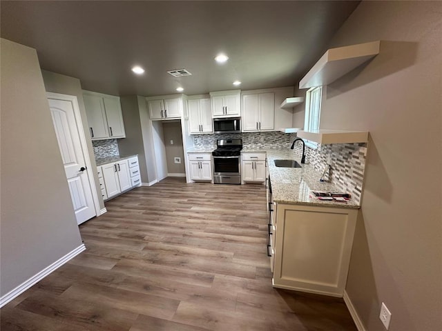 kitchen featuring light stone counters, visible vents, a sink, open shelves, and stainless steel appliances