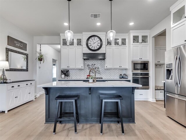 15936 Buffalo Dr, Oklahoma City, OK 73170 - kitchen with light wood-style flooring, appliances with stainless steel finishes, white cabinets, backsplash, and visible vents