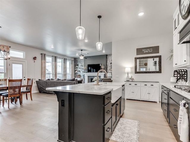 15936 Buffalo Dr, Oklahoma City, OK 73170 - kitchen with an island with sink, white cabinets, light wood finished floors, a fireplace, and a sink