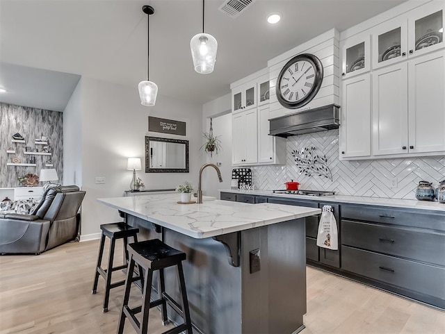 15936 Buffalo Dr, Oklahoma City, OK 73170 - kitchen with light stone counters, visible vents, an island with sink, and backsplash