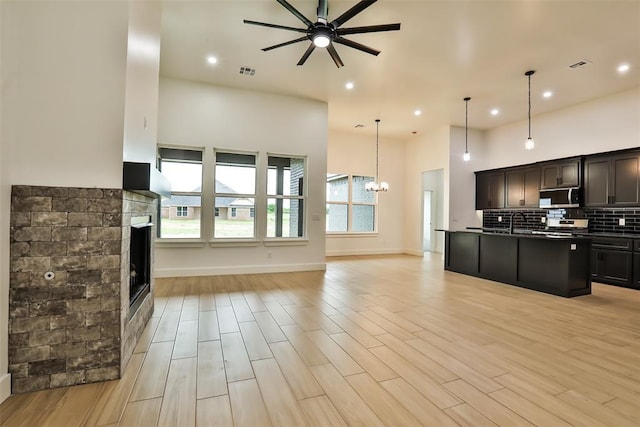 kitchen with visible vents, appliances with stainless steel finishes, a fireplace, ceiling fan with notable chandelier, and open floor plan