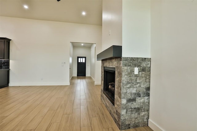 unfurnished living room featuring a fireplace, recessed lighting, baseboards, and light wood-type flooring