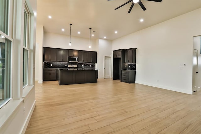kitchen featuring backsplash, a ceiling fan, stainless steel microwave, and open floor plan