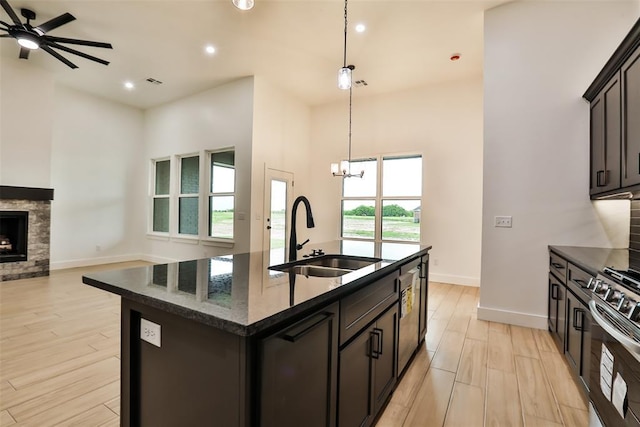 kitchen featuring a sink, light wood-style floors, stainless steel appliances, baseboards, and open floor plan