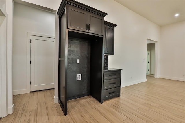 kitchen with baseboards, recessed lighting, light wood finished floors, and dark countertops