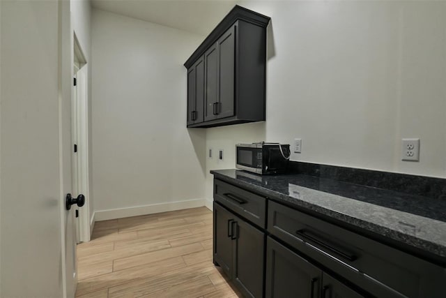 clothes washing area featuring baseboards and light wood-style flooring