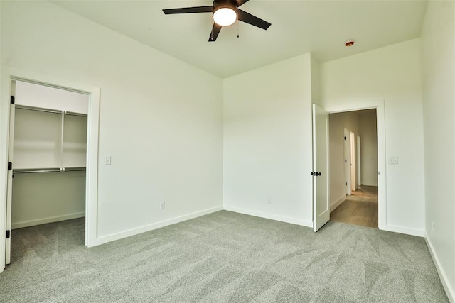 unfurnished bedroom featuring a walk in closet, a ceiling fan, baseboards, a closet, and carpet