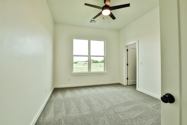 carpeted empty room with baseboards, a ceiling fan, and visible vents