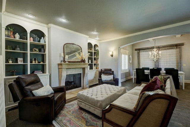 living area with baseboards, a chandelier, ornamental molding, and built in shelves