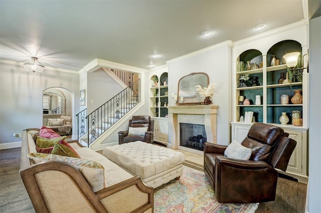 living area featuring a high end fireplace, built in features, arched walkways, ornamental molding, and stairs