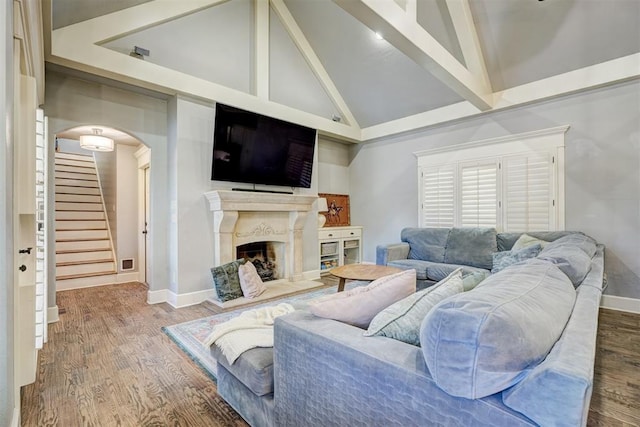 living area featuring arched walkways, high vaulted ceiling, stairs, wood finished floors, and beamed ceiling