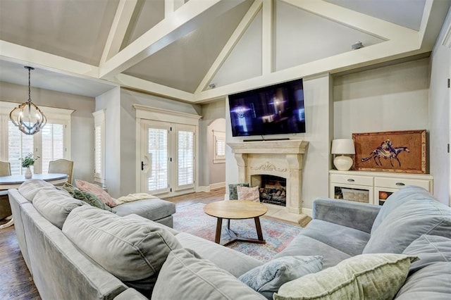 living room with high vaulted ceiling, a notable chandelier, wood finished floors, and a high end fireplace