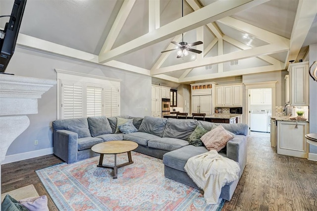living room with washer / dryer, wood finished floors, beam ceiling, baseboards, and high vaulted ceiling