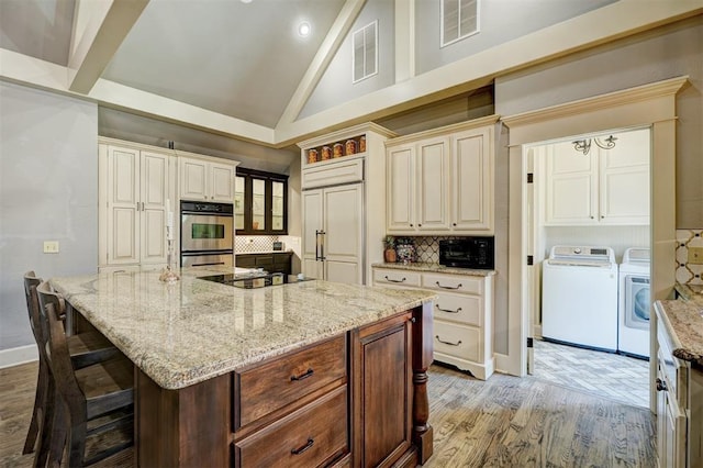 kitchen featuring backsplash, visible vents, black electric cooktop, double oven, and separate washer and dryer