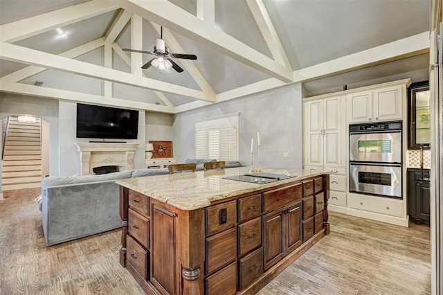 kitchen featuring open floor plan, high vaulted ceiling, stainless steel double oven, black electric cooktop, and light stone counters