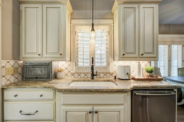 kitchen with cream cabinets, decorative backsplash, a sink, and dishwasher