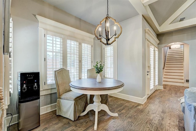 dining room featuring stairs, wood finished floors, baseboards, a chandelier, and arched walkways