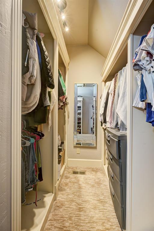 spacious closet featuring carpet floors, vaulted ceiling, and visible vents
