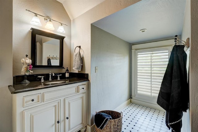 bathroom with vanity, baseboards, and a textured wall