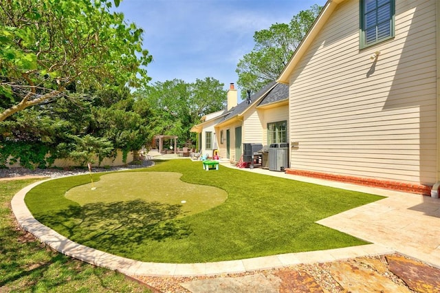 view of yard with central air condition unit and a patio