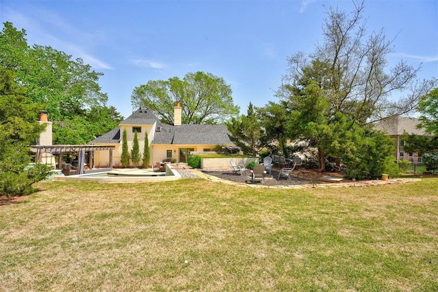 back of house featuring a lawn, a patio, and a chimney