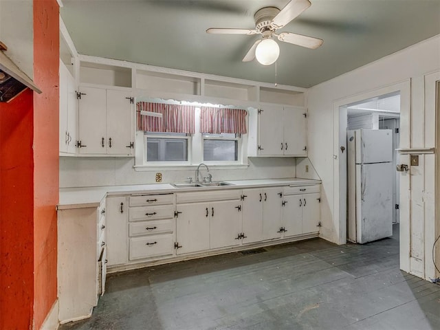 kitchen with a ceiling fan, a sink, light countertops, white cabinets, and freestanding refrigerator
