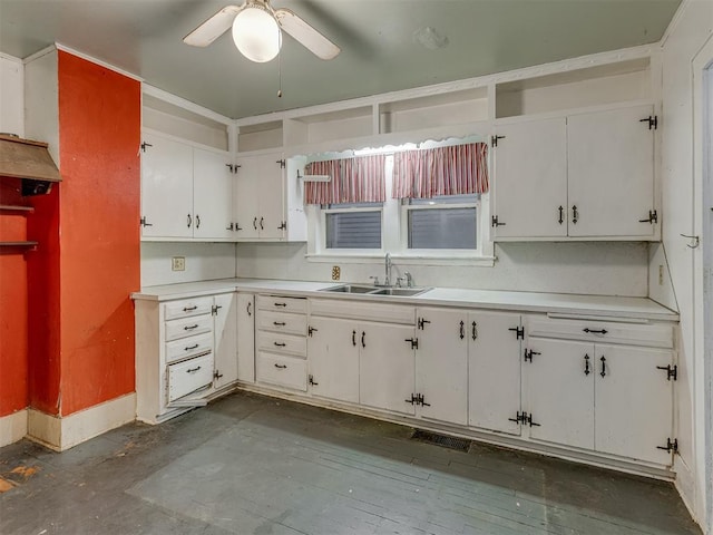 kitchen with white cabinets, ceiling fan, a sink, light countertops, and baseboards