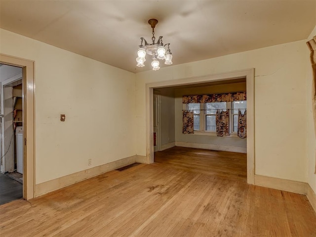 unfurnished dining area with baseboards, visible vents, light wood-type flooring, and a notable chandelier