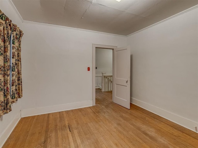 unfurnished room featuring baseboards, ornamental molding, and light wood finished floors
