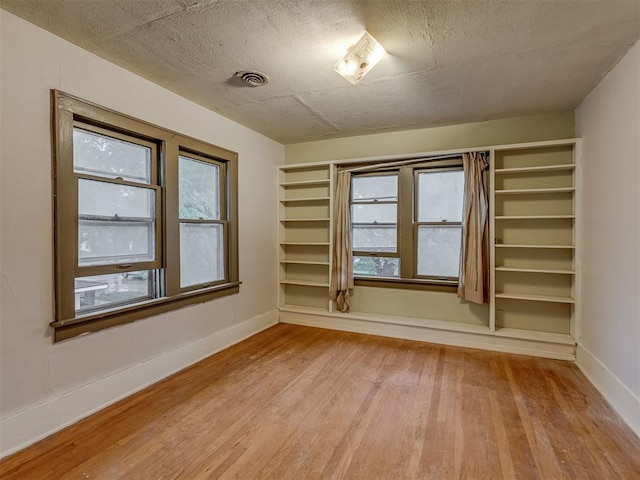 spare room with baseboards, wood finished floors, and visible vents