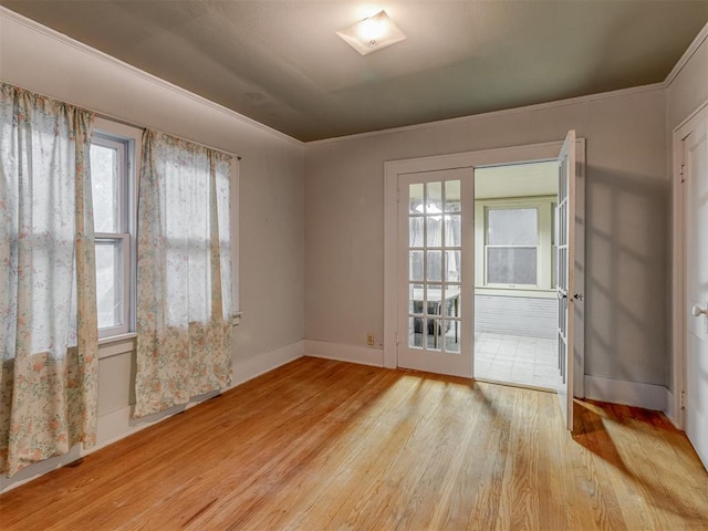 spare room featuring crown molding, baseboards, and wood finished floors
