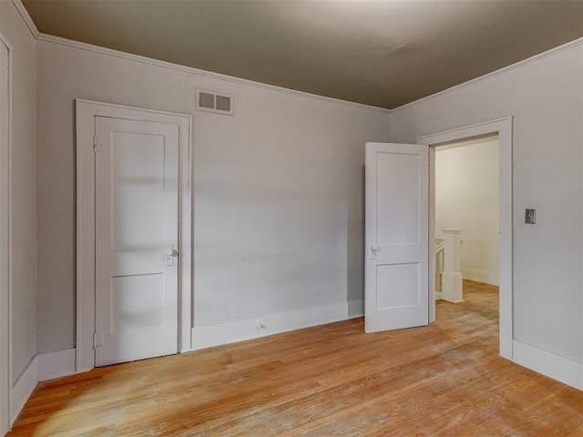 unfurnished bedroom with crown molding, baseboards, visible vents, and light wood finished floors