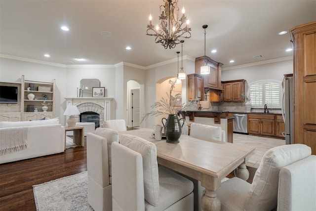 dining room with recessed lighting, a chandelier, a glass covered fireplace, crown molding, and arched walkways