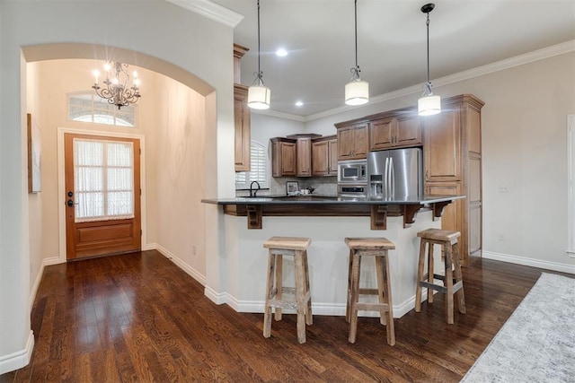 kitchen with dark wood-style floors, arched walkways, a breakfast bar, and appliances with stainless steel finishes