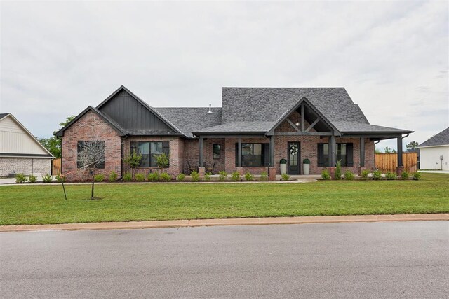 craftsman-style home featuring brick siding, board and batten siding, a shingled roof, and a front yard