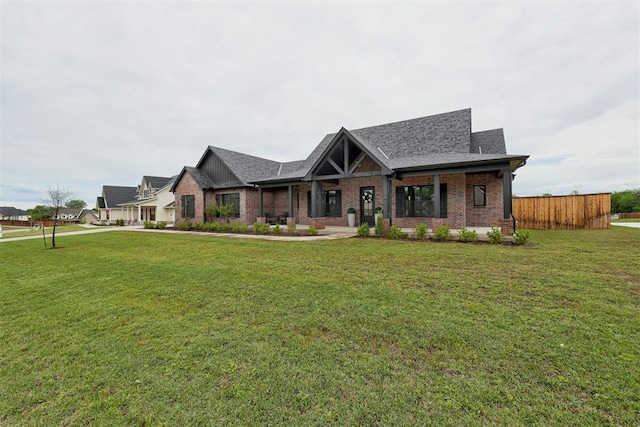 craftsman inspired home featuring a front lawn, fence, roof with shingles, and brick siding