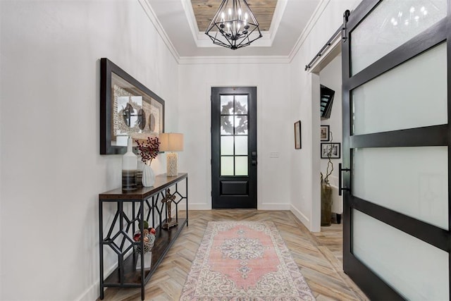 foyer entrance featuring baseboards, a barn door, ornamental molding, and an inviting chandelier