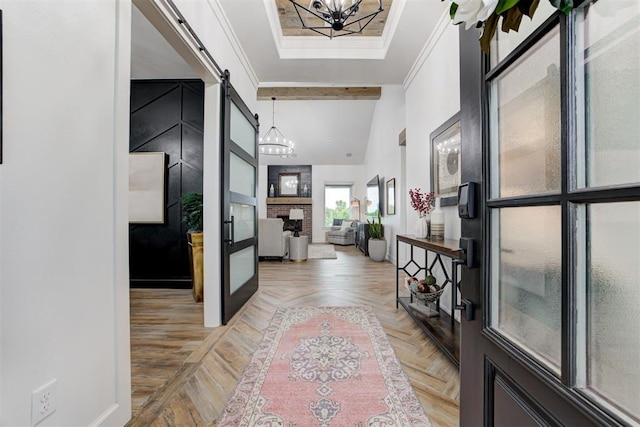 entryway featuring a barn door, baseboards, a notable chandelier, and a high ceiling