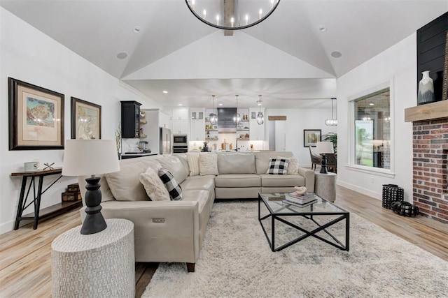living area featuring a notable chandelier, baseboards, high vaulted ceiling, and light wood-type flooring