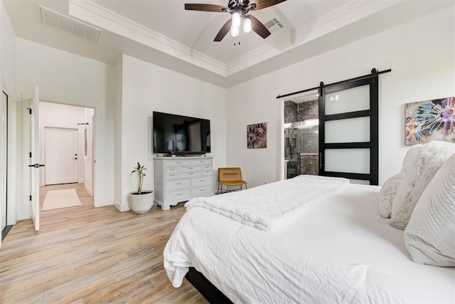 bedroom with a barn door, light wood finished floors, baseboards, visible vents, and crown molding