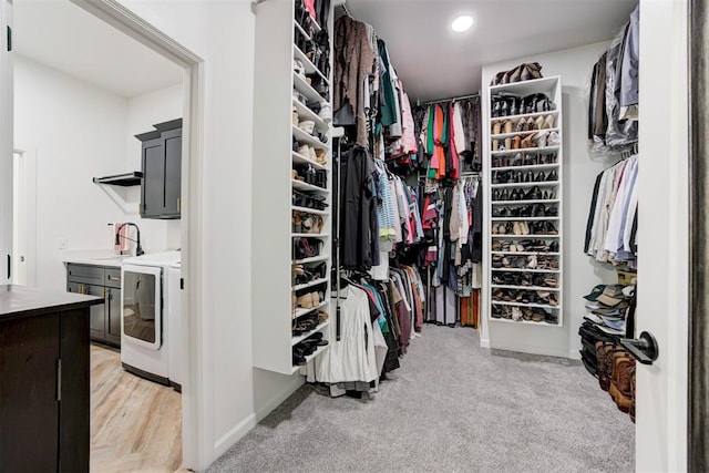 spacious closet featuring light carpet, separate washer and dryer, and a sink